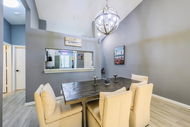 dining space with a chandelier, wood finished floors, lofted ceiling, and baseboards