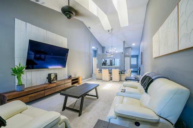 living room featuring a chandelier, high vaulted ceiling, a skylight, and carpet