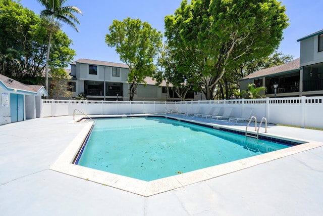 community pool featuring fence, a patio, and a residential view