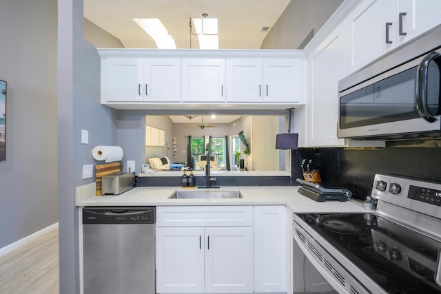 kitchen featuring stainless steel appliances, a sink, light countertops, and white cabinetry