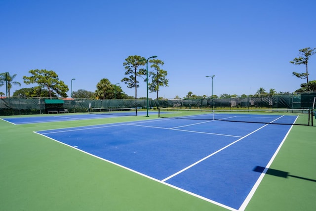 view of tennis court featuring fence and community basketball court