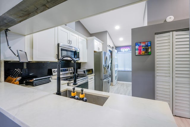 kitchen with stainless steel appliances, white cabinetry, light wood-style flooring, decorative backsplash, and light stone countertops