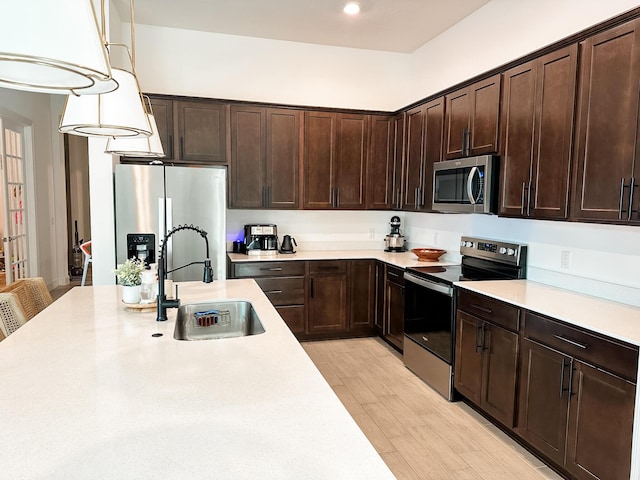 9865 SW Meridian Way, Stuart, FL 34997 - kitchen featuring stainless steel appliances, light countertops, dark brown cabinetry, light wood-type flooring, and pendant lighting