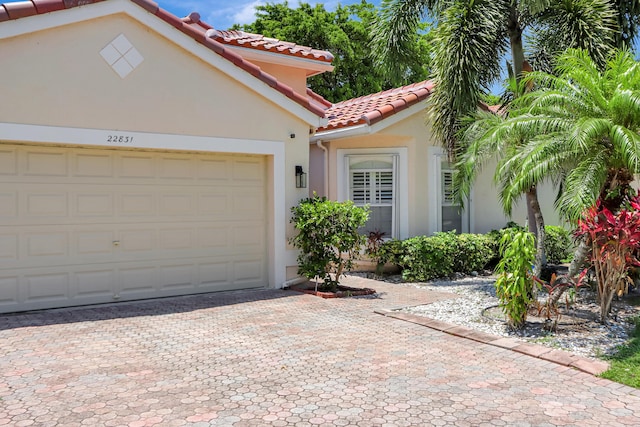 22831 Royal Crown Ter, Boca Raton, FL 33433 - mediterranean / spanish-style home with a tiled roof, stucco siding, decorative driveway, and an attached garage