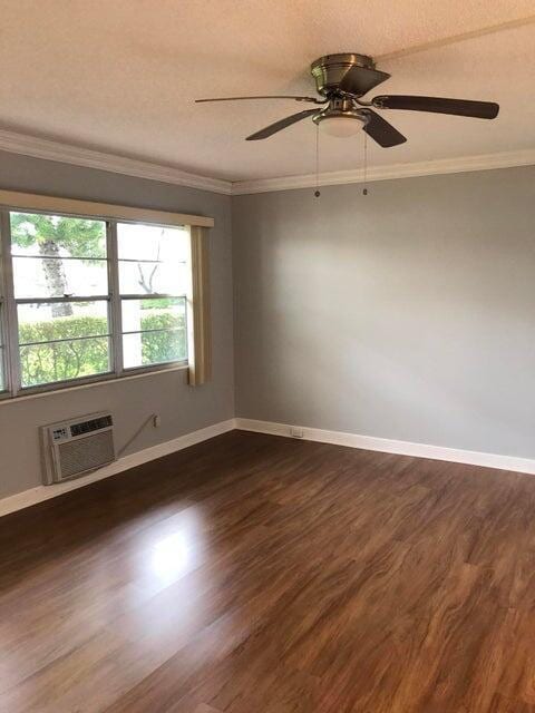261 Suffolk Unit G, Boca Raton, FL 33434 - unfurnished room with dark wood-style flooring, an AC wall unit, baseboards, ceiling fan, and ornamental molding