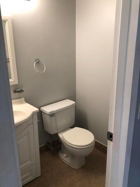 261 Suffolk Unit G, Boca Raton, FL 33434 - half bath featuring toilet, vanity, baseboards, and tile patterned flooring
