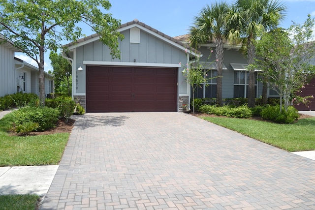 19579 Weathervane Way, The Acreage, FL 33470 - view of front of home with stone siding, an attached garage, decorative driveway, and board and batten siding