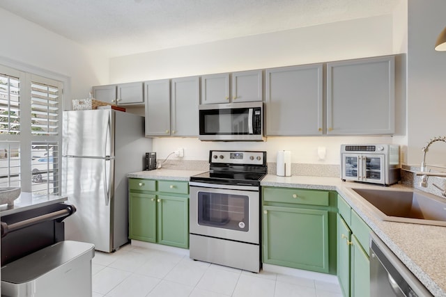 6936 Stoney Creek Cir, Lake Worth, FL 33467 - kitchen with appliances with stainless steel finishes, a sink, green cabinets, light countertops, and light tile patterned floors