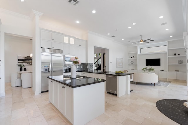 kitchen with stainless steel appliances, a peninsula, crown molding, recessed lighting, and a kitchen island