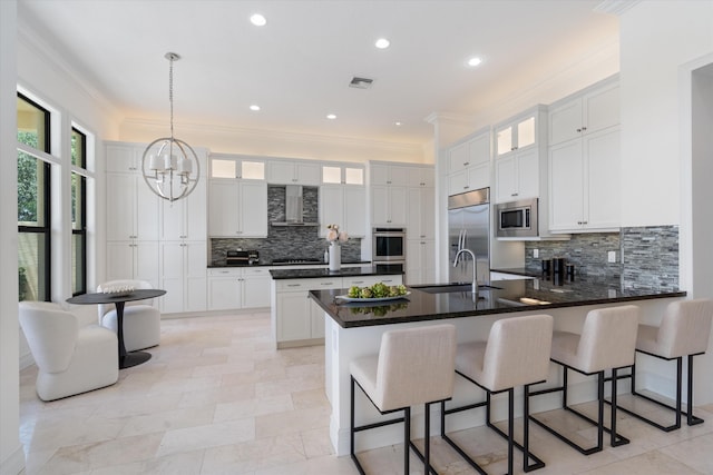 kitchen featuring built in appliances, a peninsula, wall chimney range hood, a sink, and decorative backsplash