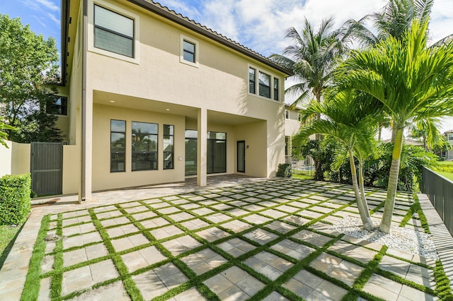 rear view of property with stucco siding, fence, and a patio area