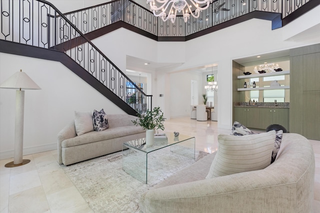 living room with a chandelier, stairway, a towering ceiling, baseboards, and marble finish floors