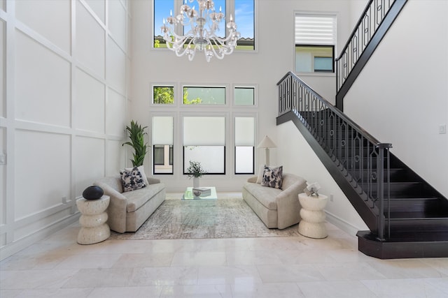 living room with a towering ceiling, a chandelier, stairs, and plenty of natural light