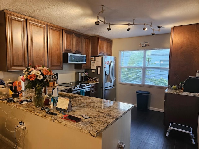 24 Bedford Ct Unit A, Royal Palm Beach, FL 33411 - kitchen with stainless steel appliances, light stone countertops, brown cabinets, baseboards, and dark wood-style flooring