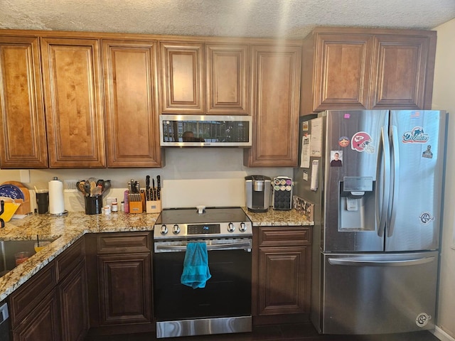 24 Bedford Ct Unit A, Royal Palm Beach, FL 33411 - kitchen featuring appliances with stainless steel finishes, light stone countertops, and a textured ceiling
