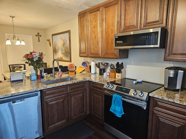 24 Bedford Ct Unit A, Royal Palm Beach, FL 33411 - kitchen with appliances with stainless steel finishes, a sink, a peninsula, light stone counters, and hanging light fixtures