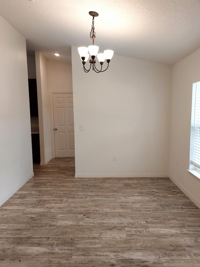 1614 SW Sylvester Ln, Port Saint Lucie, FL 34984 - unfurnished room with a chandelier, wood finished floors, baseboards, and a textured ceiling
