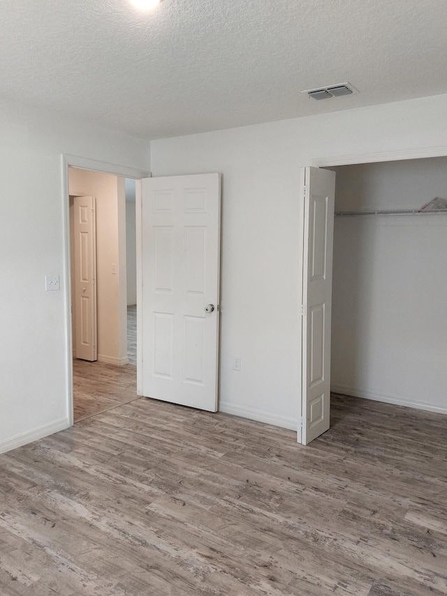 1614 SW Sylvester Ln, Port Saint Lucie, FL 34984 - unfurnished bedroom with wood finished floors, a closet, a textured ceiling, and baseboards