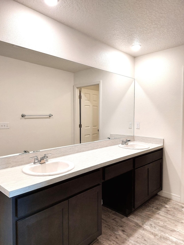 1614 SW Sylvester Ln, Port Saint Lucie, FL 34984 - bathroom featuring double vanity, wood finished floors, and a textured ceiling