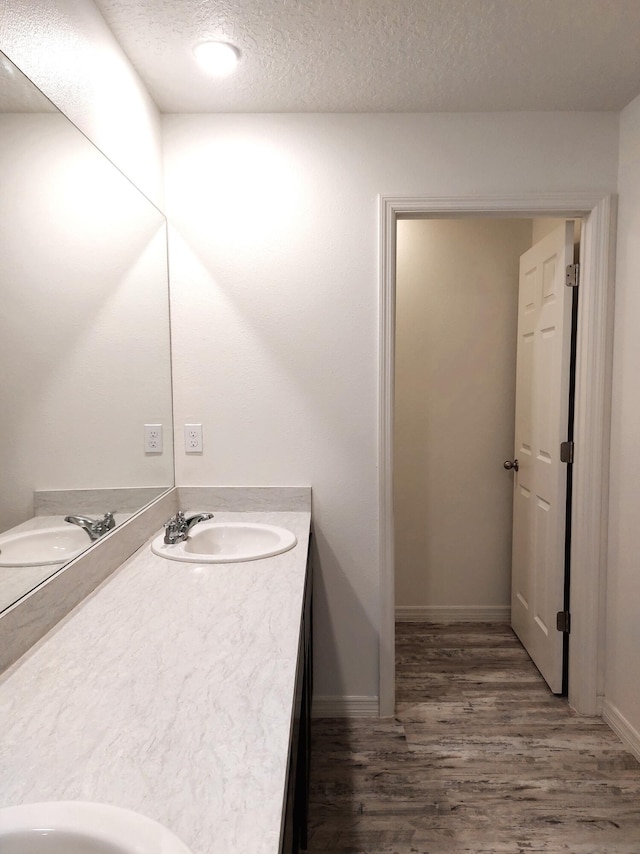 1614 SW Sylvester Ln, Port Saint Lucie, FL 34984 - bathroom with wood finished floors, double vanity, a textured ceiling, and baseboards