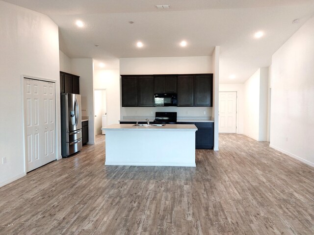 1614 SW Sylvester Ln, Port Saint Lucie, FL 34984 - kitchen with black appliances, light wood finished floors, a sink, a kitchen island with sink, and recessed lighting