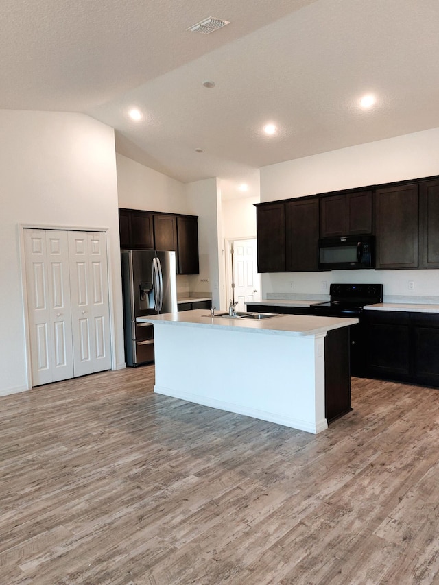 1614 SW Sylvester Ln, Port Saint Lucie, FL 34984 - kitchen featuring black appliances, light wood finished floors, a kitchen island with sink, vaulted ceiling, and light countertops