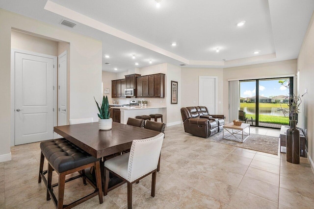 4817 Saint Armands Way, Westlake, FL 33470 - dining room with a tray ceiling, baseboards, recessed lighting, a water view, and light tile patterned flooring