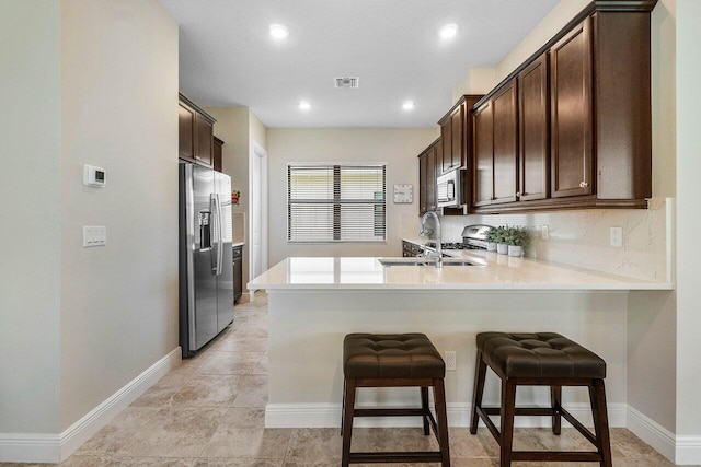 4817 Saint Armands Way, Westlake, FL 33470 - kitchen with appliances with stainless steel finishes, dark brown cabinetry, a peninsula, a sink, and light countertops