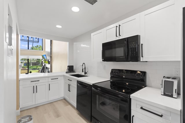 10650 NW 30th Pl Unit 1, Sunrise, FL 33322 - kitchen featuring black appliances, a sink, decorative backsplash, light wood finished floors, and white cabinetry
