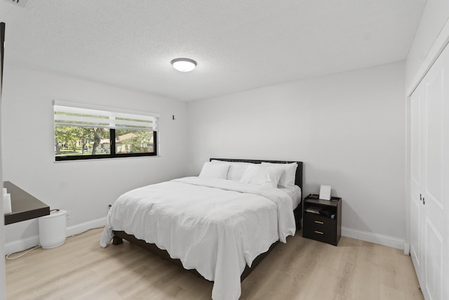 10650 NW 30th Pl Unit 1, Sunrise, FL 33322 - bedroom featuring light wood finished floors, a closet, a textured ceiling, and baseboards