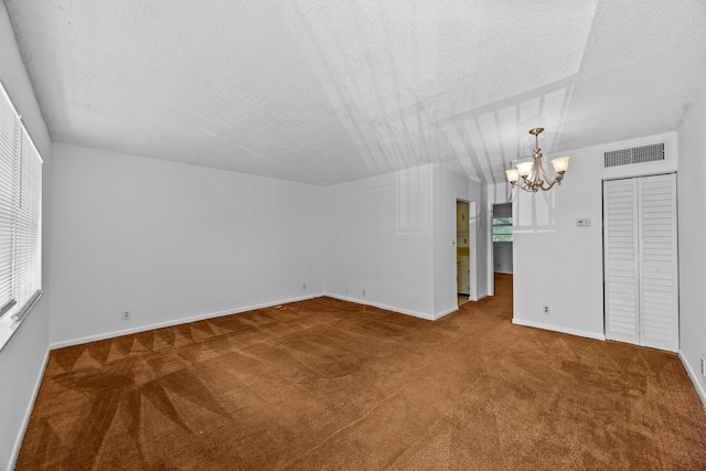 300 NW 30th Ct Unit 202, Pompano Beach, FL 33064 - empty room featuring carpet flooring, a chandelier, healthy amount of natural light, a textured ceiling, and baseboards