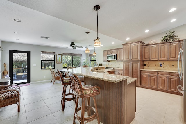 11195 N 159th Ct N, Jupiter, FL 33478 - kitchen with stainless steel appliances, recessed lighting, decorative backsplash, light stone countertops, and a breakfast bar