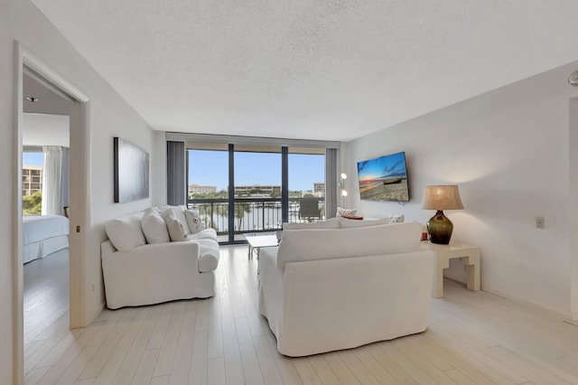 2697 N Ocean Blvd Unit 407-F, Boca Raton, FL 33431 - living area with healthy amount of natural light, a textured ceiling, light wood finished floors, and floor to ceiling windows