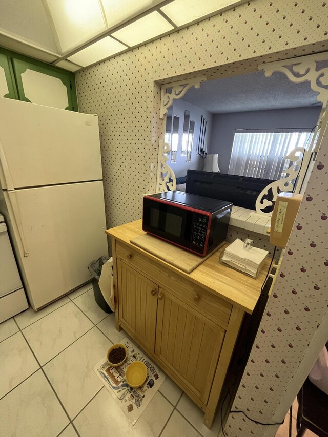 262 Sussex M, West Palm Beach, FL 33417 - kitchen with black microwave, freestanding refrigerator, wood counters, light tile patterned floors, and wallpapered walls