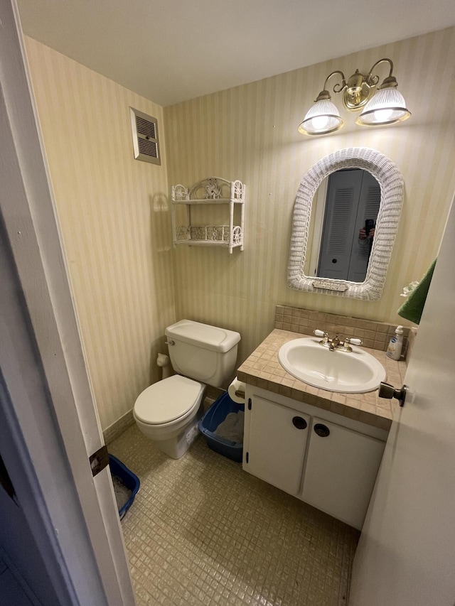 262 Sussex M, West Palm Beach, FL 33417 - half bathroom with toilet, vanity, and wallpapered walls