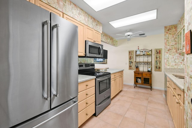 17187 Bay St, Jupiter, FL 33477 - kitchen with appliances with stainless steel finishes, light brown cabinets, decorative backsplash, light tile patterned floors, and a skylight