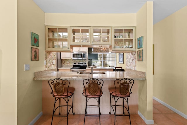 17187 Bay St, Jupiter, FL 33477 - kitchen featuring a sink, stainless steel appliances, a peninsula, and light stone countertops