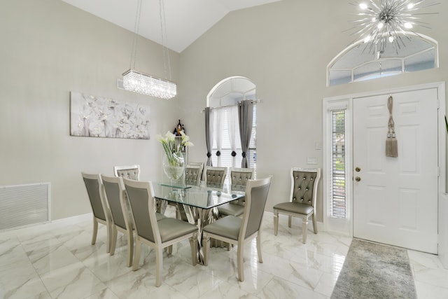 dining space featuring a chandelier, marble finish flooring, high vaulted ceiling, and baseboards