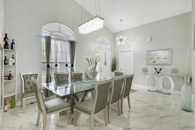 dining room with light marble finish floors, high vaulted ceiling, a chandelier, baseboards, and plenty of natural light