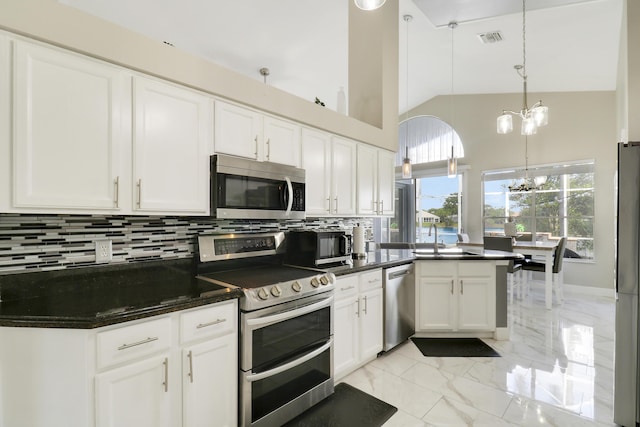 kitchen with appliances with stainless steel finishes, a chandelier, decorative backsplash, light marble finish floors, and white cabinets