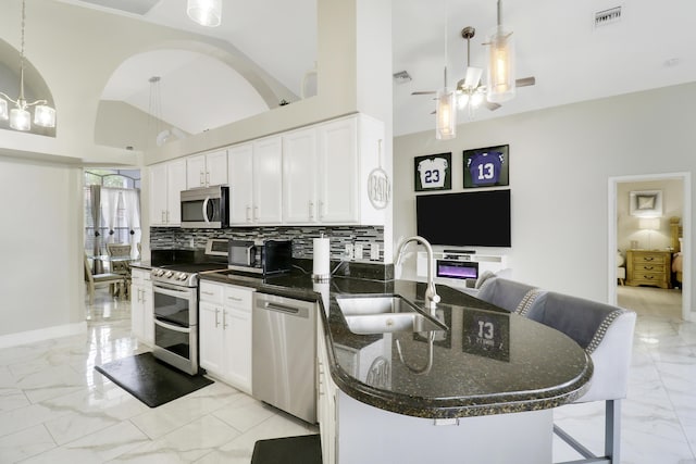 kitchen with appliances with stainless steel finishes, a sink, light marble finish floors, a peninsula, and ceiling fan