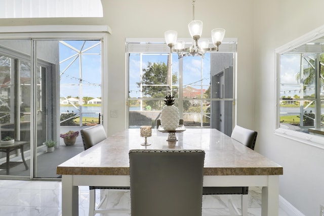 dining space with marble finish floors, a chandelier, baseboards, and plenty of natural light
