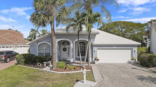 view of front of property featuring a garage, driveway, stucco siding, a tiled roof, and a front yard