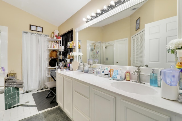 bathroom featuring a stall shower, vaulted ceiling, tile patterned floors, and double vanity