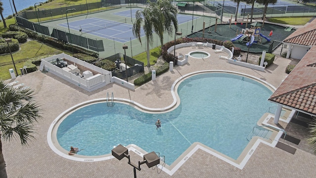 community pool with fence, a tennis court, and a community hot tub