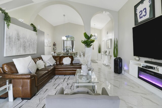 living room with arched walkways, marble finish floors, vaulted ceiling, a chandelier, and baseboards