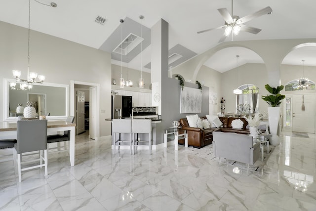 living area with a chandelier, high vaulted ceiling, arched walkways, ceiling fan, and light marble finish flooring