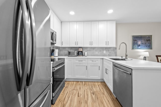 3561 Pine Tree Ct Unit A-2, Greenacres, FL 33463 - kitchen featuring stainless steel appliances, a sink, a peninsula, light wood-style floors, and white cabinetry