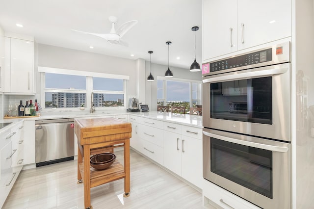 400 Seasage Dr Unit 805, Delray Beach, FL 33483 - kitchen with appliances with stainless steel finishes, a sink, light countertops, white cabinetry, and decorative light fixtures