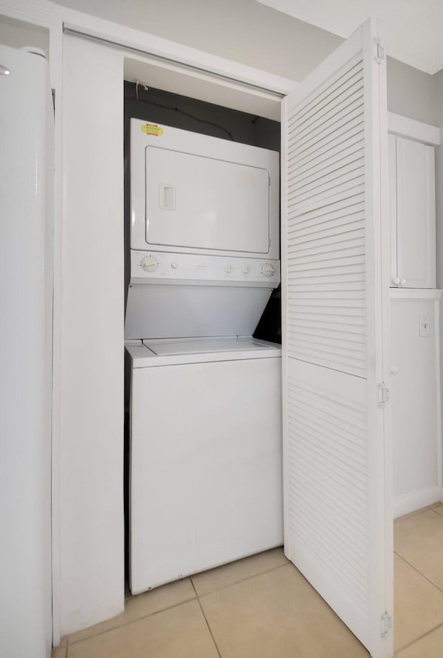 washroom featuring stacked washing machine and dryer and light tile patterned flooring